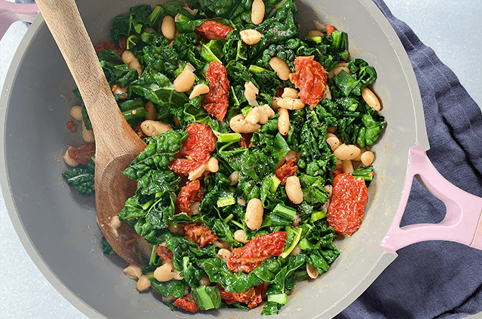 Kale & White Bean Skillet being served with a wood spoon