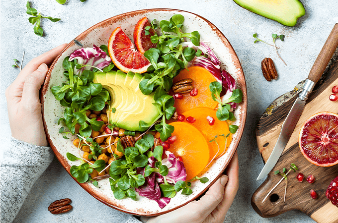 Vegan salad in a bowl that someone is holding with 2 hands