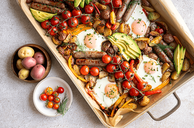 Sheet Pan Breakfast Hash plated on wooden table served with a side of potatoes and tomatoes