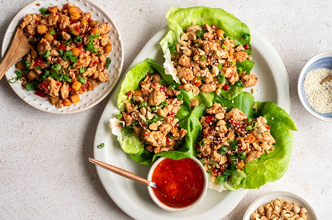 Teriyaki chicken lettuce wraps plated with a side of sweet chili sauce