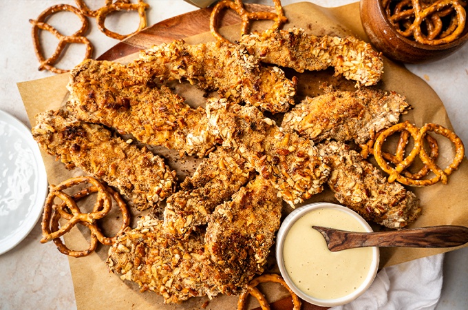 Pretzel crusted chicken tenders plated with honey mustard dipping sauce