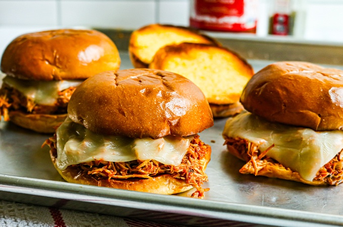 Slow Cooker Chicken Parmesan sandwiches on a sheet tray