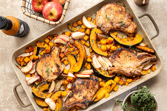 Pan-Seared Pork Chops fresh out of the oven on a table surrounded by its accoutrements