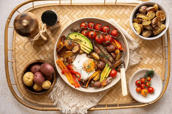 Sheet Pan Breakfast Hash plated on wooden table served with a side of potatoes and tomatoes
