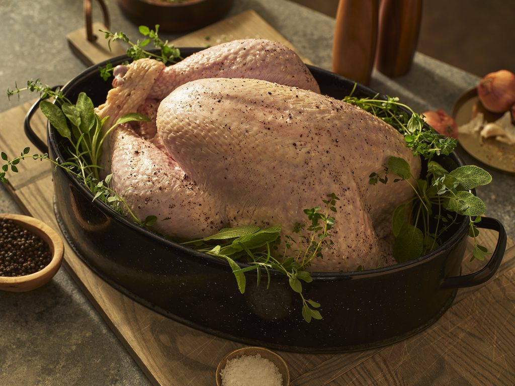 A fresh, uncooked turkey seasoned for a holiday meal.