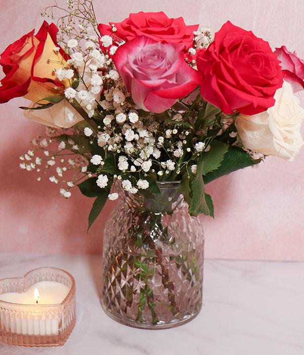 Pink Red and White Roses in a Vase with a Candle Beside