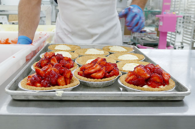 A baker assembling strawberry cream cheese pies