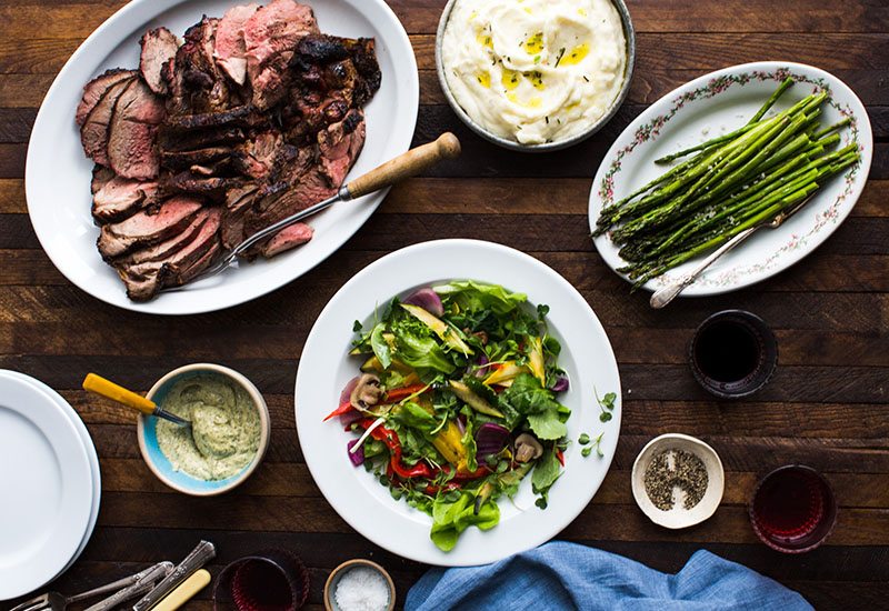 Lamb, mashed potatoes, asparagus, and a salad on a table