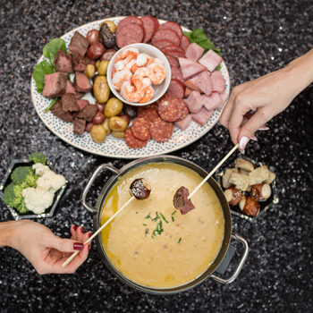 Different Foods being dipped into a pot of fondue