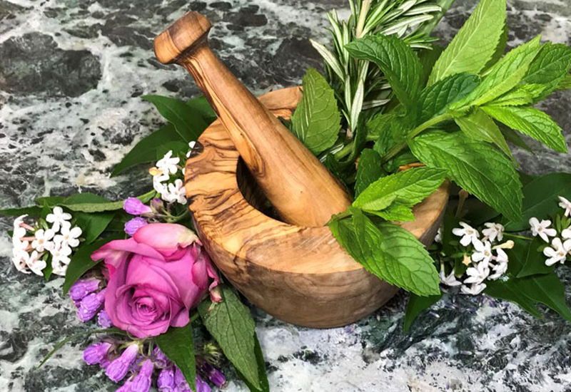 Mortar and pestle with flowers and herbs