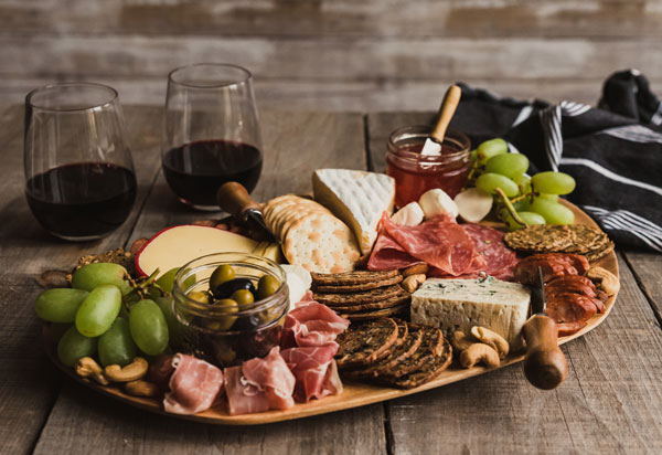 Charcuterie board with two glasses of red wine
