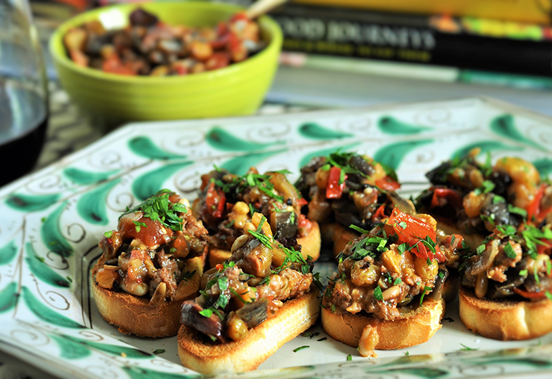 Eggplant caponata with spicy sausage served on slices of bread