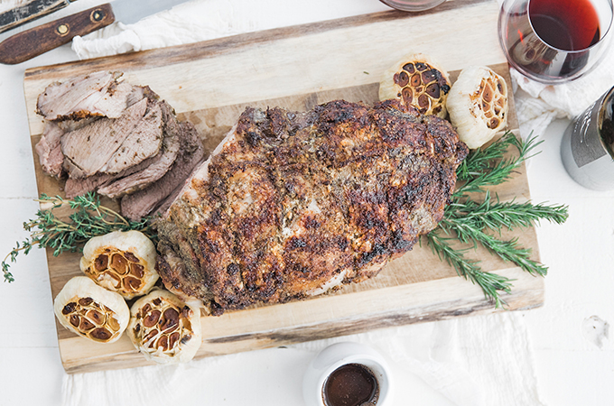 Herb and Garlic Roasted Lamb with Red Wine Sauce on cutting board
