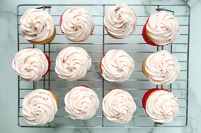 Frosted strawberry prosecco cupcakes on wire rack