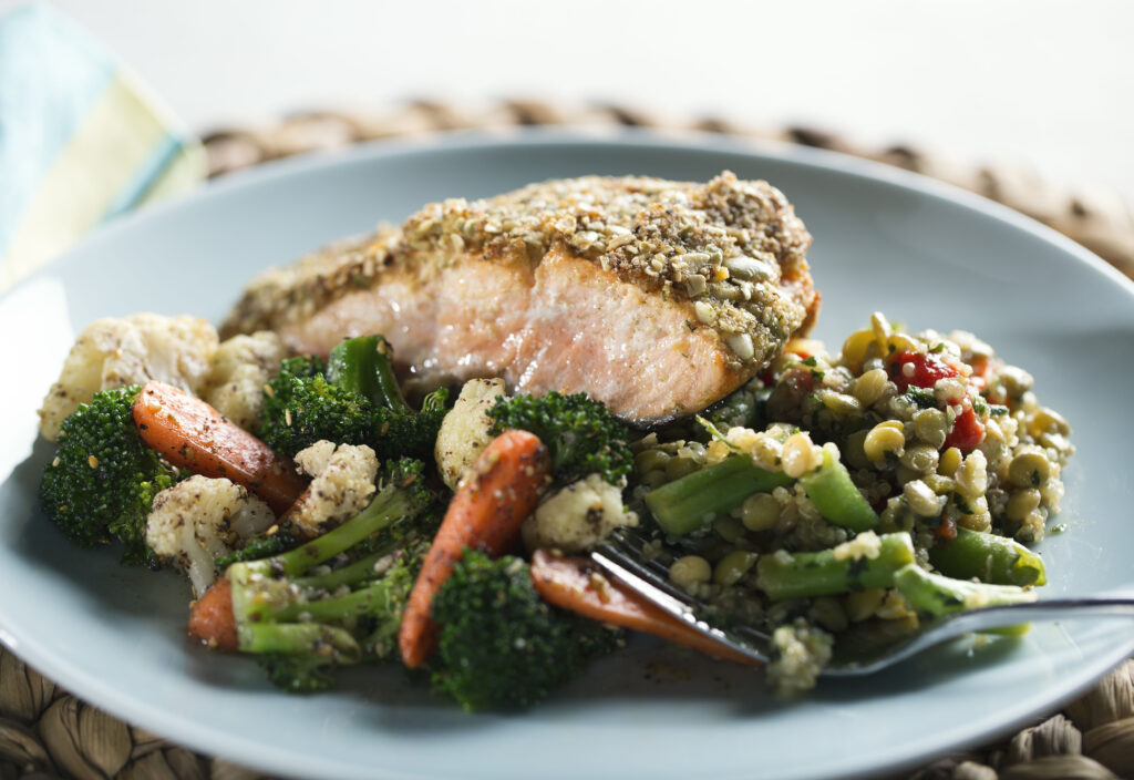 Pepita crusted salmon with veggies on a blue plate