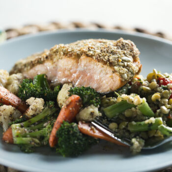 Pepita crusted salmon with veggies on a blue plate