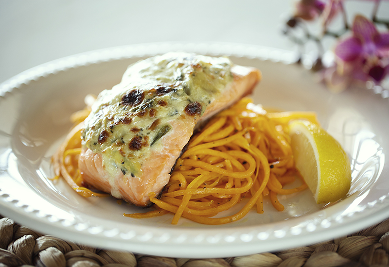 Spinach and artichoke crusted salmon served over veggie noodles