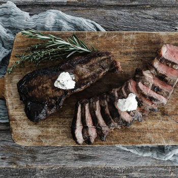 Steak sliced with butter on wooden cutting board