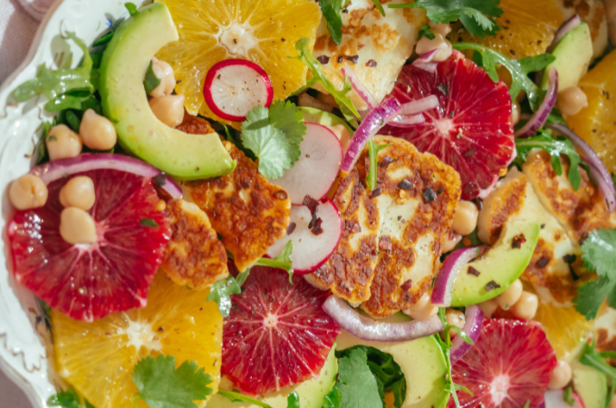 Halloumi cheese salad with fresh citrus in big white bowl 