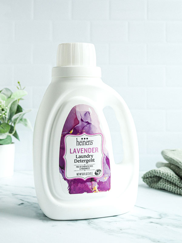 Heinen's Lavender Landry Detergent Bottle with a Green Plant and Fresh Towels 