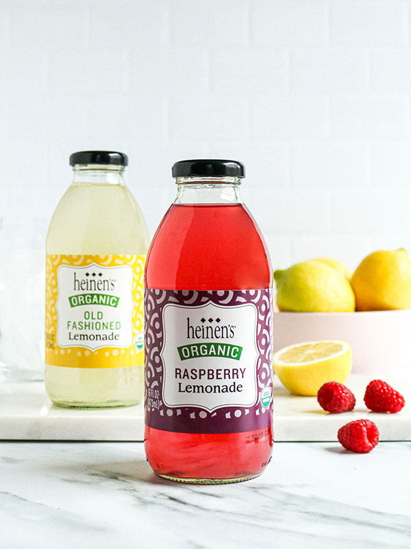  Heinen's Organic Bottled Lemonades with a Bowl of Fresh Lemons and Raspberries
