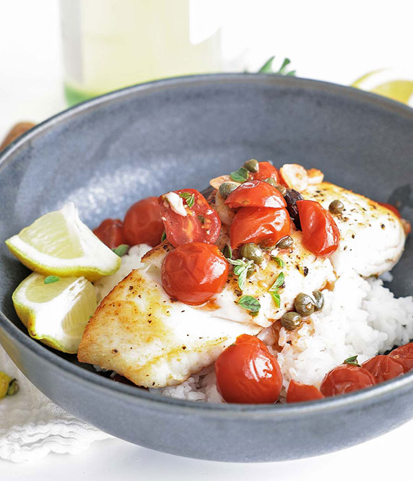 Mediterranean Halibut in a Bowl with Rice, Cherry Tomatoes, Olives and Lemon.