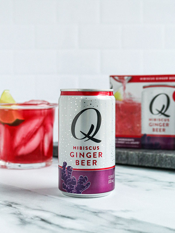 Q Mixers Hibiscus Ginger Beer Can with Q Mixers Box and a Filled Glass