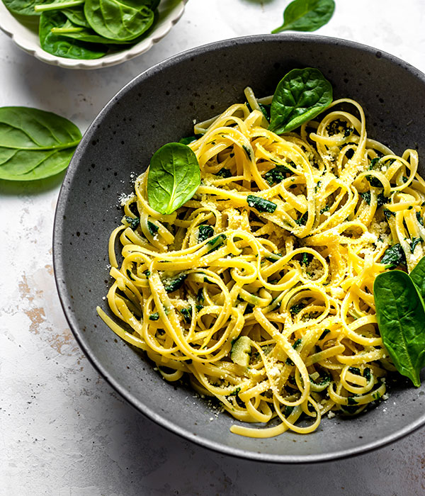 Spinach Parmesan Pasta in a Bowl with a Bowl of Spinach Beside