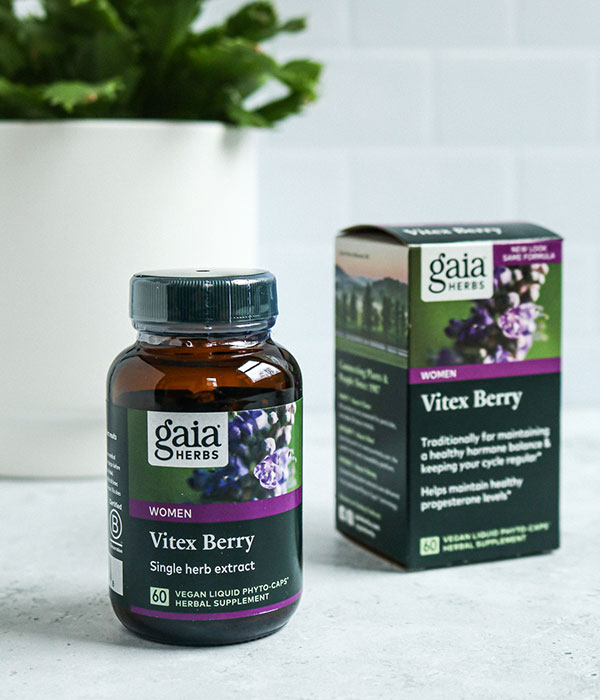 Gaia Supplement Box and Bottle on a Slate Gray Surface with a subway tile background and a plant.
