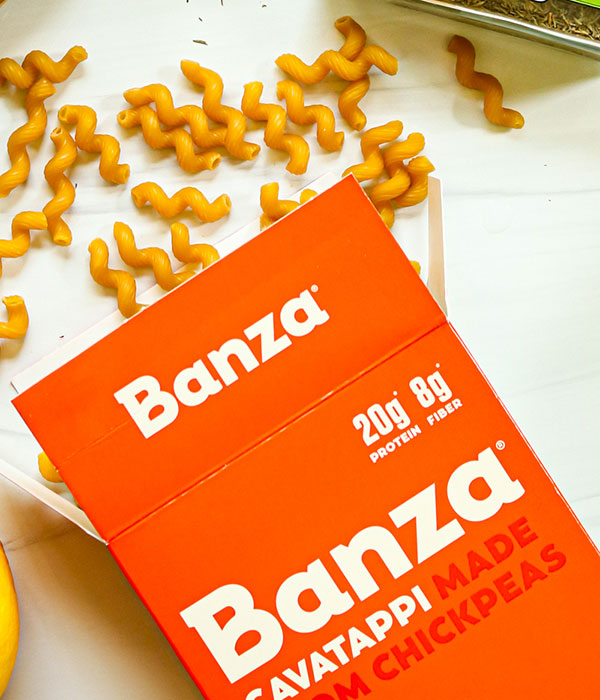 A Box of Banza Pasta on a White Surface with Noodles Coming Out of the Box