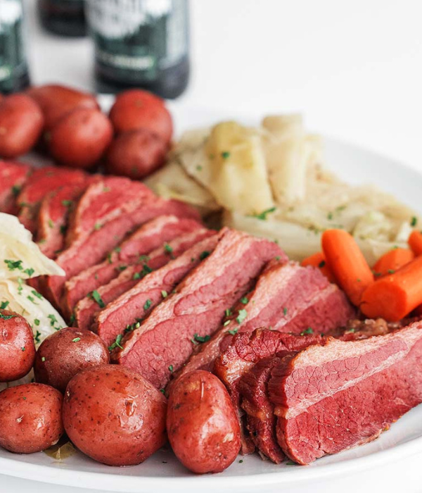 zoomed in on corned beef with potatoes, carrots, and cabbage on white plate