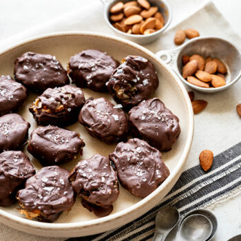 Mini Chocolate Covered Dates Snickers Bars on a Plate with Bowls of Almonds Beside