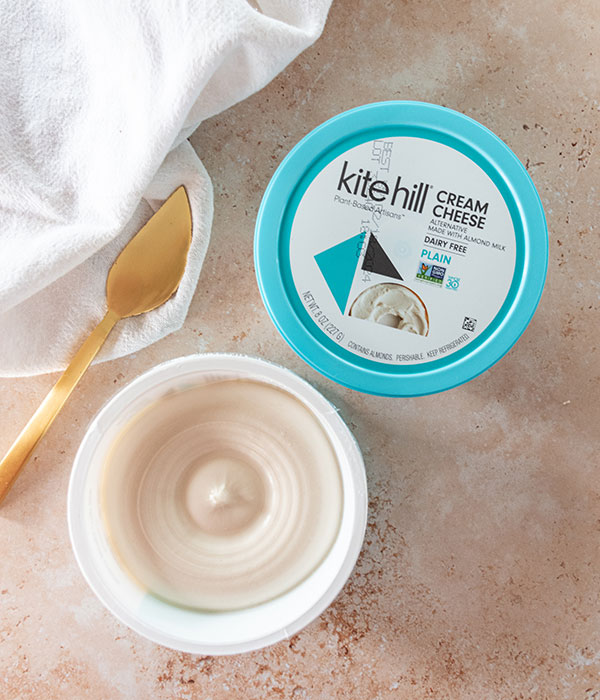 Kite Hill Cream Cheese Packaging on a Neutral Surface with a Gold Knife and White Dish Towel