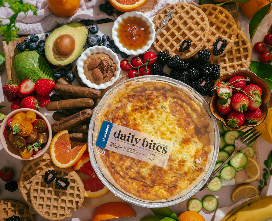 Heinen's Premade Quiche on a Serving Board with an Assortment of Colorful Brunch Food