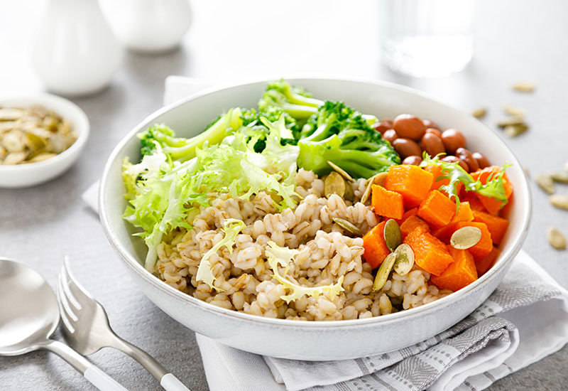A Grain Bowl Topped with Cubed Sweet Potatoes, Lettuce, Broccoli and Beans