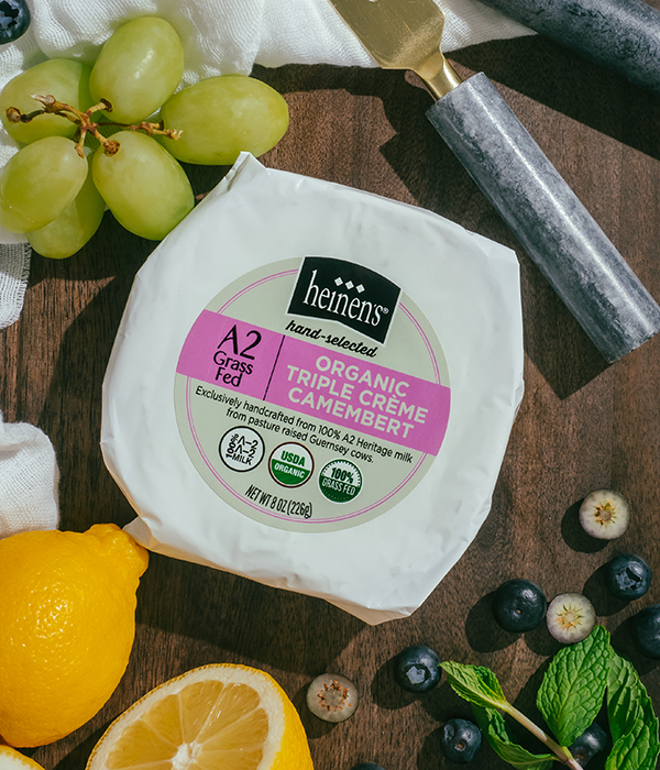 Heinen's Hand-Selected A2 Organic Triple Creme Camembert on a Dark Serving Board with Fresh Lemons, Fresh Blueberries, Fresh Herbs, Green Grapes and Cheese Servingware