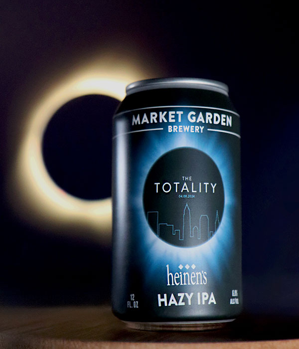 A Vertical Image of a Can of Heinen's Totality IPA Beer on a Surface with an Eclipse Behind it