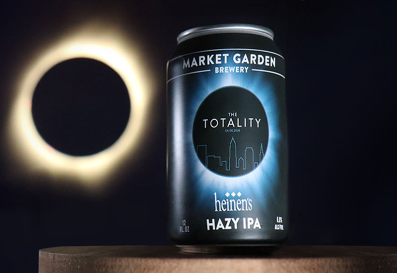 A Can of Heinen's Totality IPA Beer on a Surface with an Eclipse Behind it
